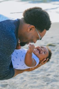 man in blue shirt holding laughing baby