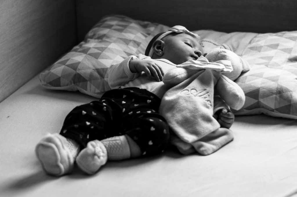 grayscale photo of baby lying on bed